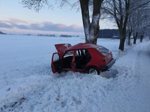 zdjęcie przedstawia czerwonego volkswagena golfa, który uderzył w drzewo