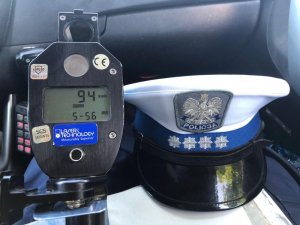 na zdjęciu znajduje się policyjna czapka funkcjonariusza ruchu drogowego, po jej lewej stronie widać przyrząd do pomiaru prędkości z wynikiem 94 km/h