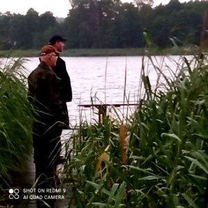 na zdjęciu widać pomost na którym stoi policjant i strażnik rybacki obserwujący jezioro