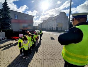 policjanta tłumaczy dzieciom zasady bezpiecznego przechodzenia przez jezdnię