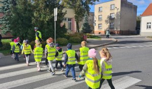 policjant uczy dzieci przechodzić przez przejścia dla pieszych