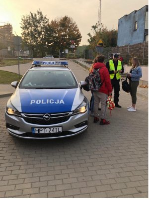 policjanci wręczają pieszemu kamizelkę odblaskową