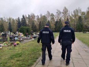 na zdjęciu widać dwóch policjantów, którzy patrolując cmentarz