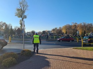 policjant nadzoruje ruch pojazdów i pieszych w rejonie cmentarza