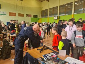 na zdjęciu widać policjanta rozmawiającego z dziećmi przy stoisku policyjnym