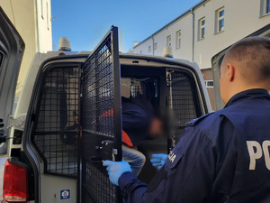na zdjęciu widać policjanta zamykającego radiowóz z zatrzymanym