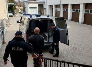 na zdjęciu widać zatrzymanego mężczyznę doprowadzanego przez umundurowanego policjanta do radiowozu