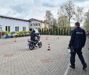 na zdjęciu widać uczestnika turnieju jadącego motorowerem i sędziującego policjanta