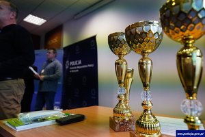 na zdjęciu widać puchary, w tle baner policyjny