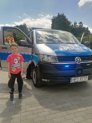 na zdjęciu widać dziecko stojące przed policynjym radiowozem