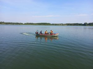 na zdjęciu widać łódź strażacką, a na niej dwóch strażaków i policjanta patrolujących teren jeziora