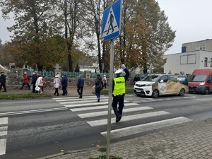 na zdjęciu widać policjanta kierującego ruchem przy cmentarzu