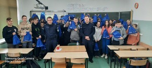 pamiątkowe zdjęcie policjantów z uczniami, którzy trzymają w rękach gadżety projektu POWER ON