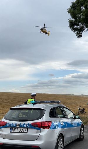 radiowóz, policjant a nad nimi helikopter
